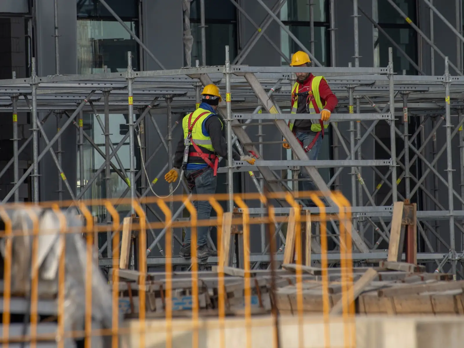 Due operai con casco e imbracatura anticaduta al lavoro su un ponteggio