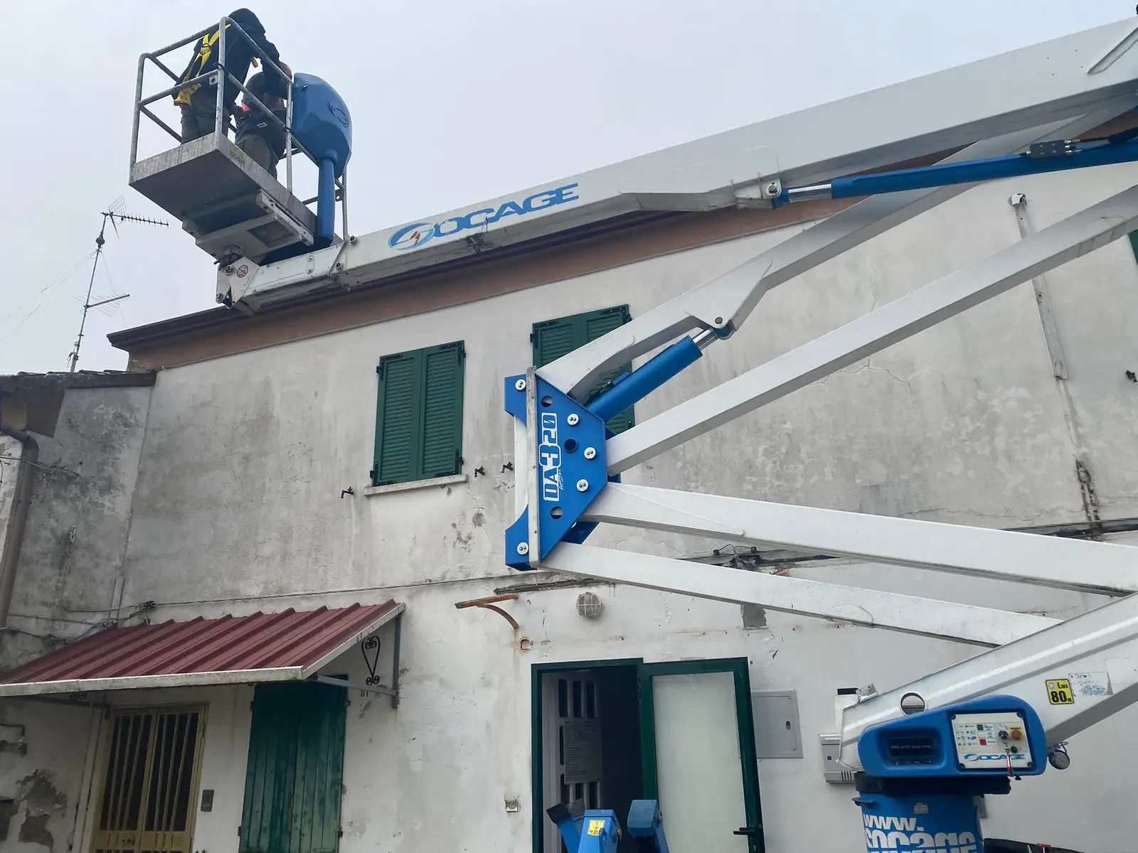 Operatore su piattaforma aerea al lavoro sulla facciata di un edificio